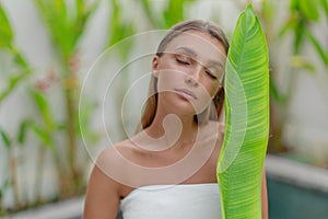 Portrait of a beautiful young girl with a green leaf. Spa treatments