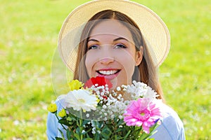 Portrait of a beautiful young girl holding bouquet of  flowers and isolated on green grass background