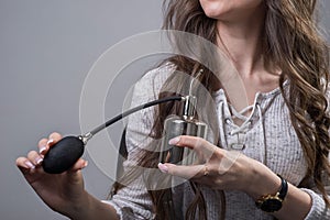 Portrait of a beautiful young girl with luxurious hair. A woman uses a bottle of perfume, enjoying the smell, looking at herself