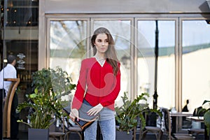 Portrait of a beautiful young girl in red shirt on the background of the urban landscape