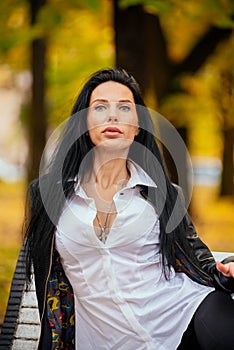 portrait of a beautiful young girl sitting on a bench in an autumn park