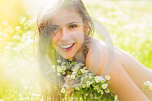 Portrait of a beautiful young girl in the spring with wildflowers. Happy summer face of young woman in green nature