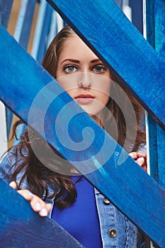 Portrait of a beautiful young girl standing behind the fence