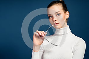 Portrait of a beautiful young girl in sunglasses on a blue background