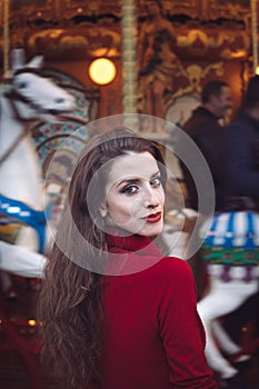 Portrait of a beautiful young girl with white cotton candy in front of a carousel horse