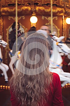 Portrait of a beautiful young girl with white cotton candy in front of a carousel horse