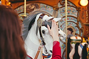 Portrait of a beautiful young girl with white cotton candy in front of a carousel horse