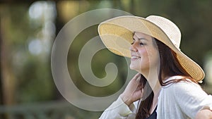 Portrait of beautiful young Hispanic woman with long hair with a hat very cheerful sitting on a park bench against a background of