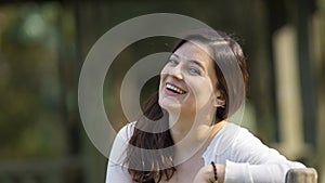 Portrait of a beautiful young Hispanic woman in the middle of a park with a very cheerful attitude against a background of