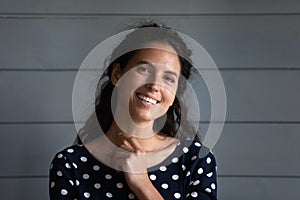 Portrait of beautiful young hispanic woman posing near grey wall.