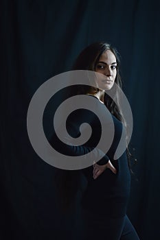 Portrait of a beautiful young Italian woman with very long brown hair who with her hand on her hip looks in a serious way