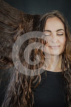 Portrait of a beautiful young Italian woman with very long brown hair who is smiling with her eyes closed