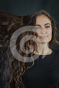 Portrait of a beautiful young Italian woman with very long brown hair who is smiling and looking at the camera