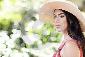 Portrait of a beautiful young Italian woman wearing a straw hat in sunny warm weather day.