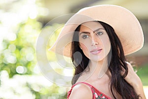 Portrait of a beautiful young Italian woman wearing a straw hat in sunny warm weather day.