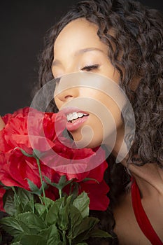 Portrait of a beautiful young Latina woman holding red flowers
