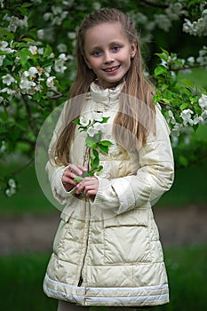 Portrait of a beautiful young long-haired girl. Adorable child having fun in blossom cherry garden on beautiful spring day