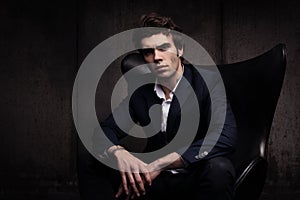 Portrait of a beautiful young man sitting in a chair. Stylish in appearance