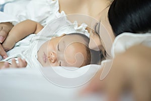 Portrait of a beautiful young mother and baby sleep in a white b