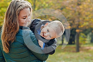 Portrait of a beautiful young mother with her son walks in the autumn park