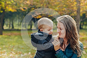 Portrait of a beautiful young mother with her son walks in the autumn park