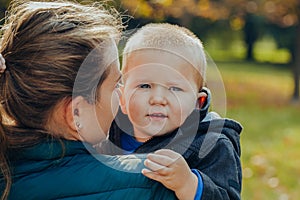 Portrait of a beautiful young mother with her son walks in the autumn park