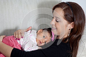 Portrait of beautiful young mother at home with her one month baby girl. Motherhood concept. Family love concept