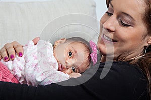 Portrait of beautiful young mother at home with her one month baby girl. Motherhood concept. Family love concept