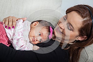 Portrait of beautiful young mother at home with her one month baby girl. Motherhood concept. Family love concept