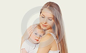 Portrait beautiful young mother hugging and soothes her baby on a white background