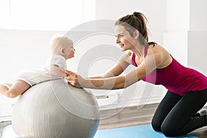 A Portrait of beautiful young mother in sports wear with her charming little baby in training session