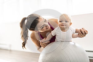 A Portrait of beautiful young mother in sports wear with her charming little baby in training session