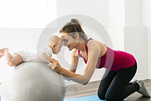 A Portrait of beautiful young mother in sports wear with her charming little baby in training session