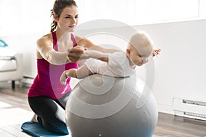 A Portrait of beautiful young mother in sports wear with her charming little baby in training session