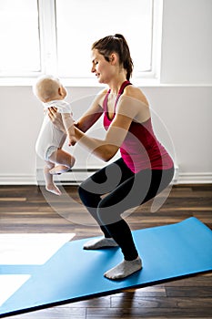 A Portrait of beautiful young mother in sports wear with her charming little baby in training session