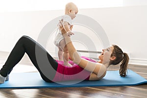 A Portrait of beautiful young mother in sports wear with her charming little baby in training session