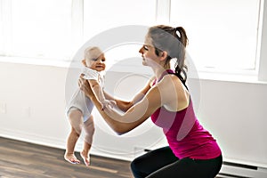 A Portrait of beautiful young mother in sports wear with her charming little baby in training session