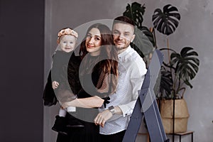 Portrait of beautiful young parents and their cute little daughter hugs, looking at camera and smiling indoors. mother`s, father