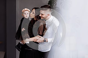 Portrait of beautiful young parents and their cute little daughter hugs, smiling indoors. mother`s, father`s, baby`s day. conce