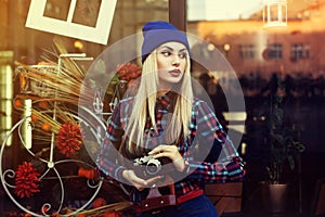 Portrait of beautiful young playful hipster woman with old retro camera. Model looking aside. City lifestyle. Toned