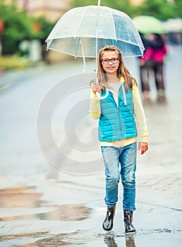 Portrait of beautiful young pre-teen girl with umbrella under rain