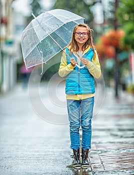 Portrait of beautiful young pre-teen girl with umbrella under rain