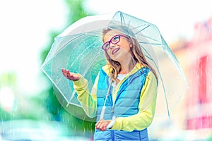 Portrait of beautiful young pre-teen girl with umbrella under rain