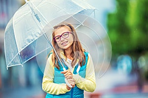 Portrait of beautiful young pre-teen girl with umbrella under rain