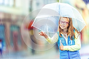 Portrait of beautiful young pre-teen girl with umbrella under rain