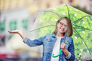 Portrait of beautiful young pre-teen girl with umbrella under rain