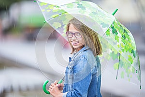 Portrait of beautiful young pre-teen girl with umbrella under spring or summer rain