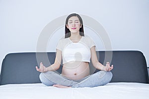 Portrait of Beautiful young pregnant woman doing yoga in her bedroom.Pregnancy health care preparing for baby concept.Motherhood