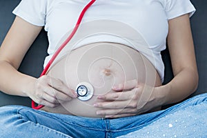 Portrait of Beautiful young pregnant women using stethoscope listening to her tummy.Pregnancy health care preparing for baby