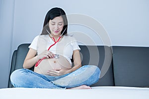Portrait of Beautiful young pregnant women using stethoscope listening to her tummy.Pregnancy health care preparing for baby